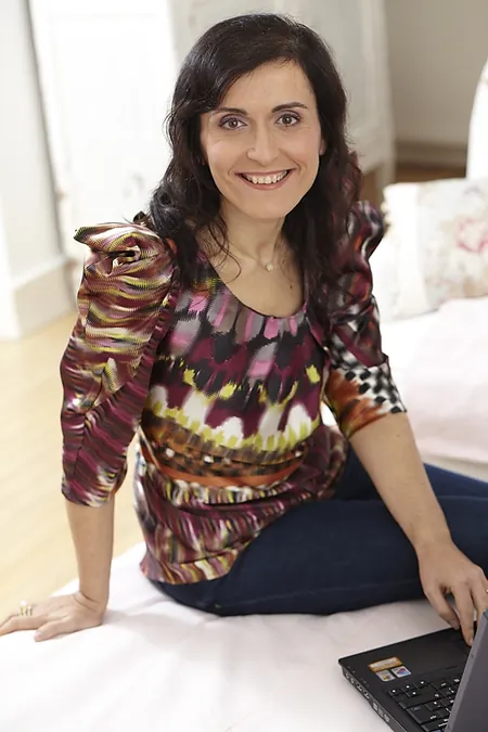 Author Julia F. Clifford smiling beside her laptop